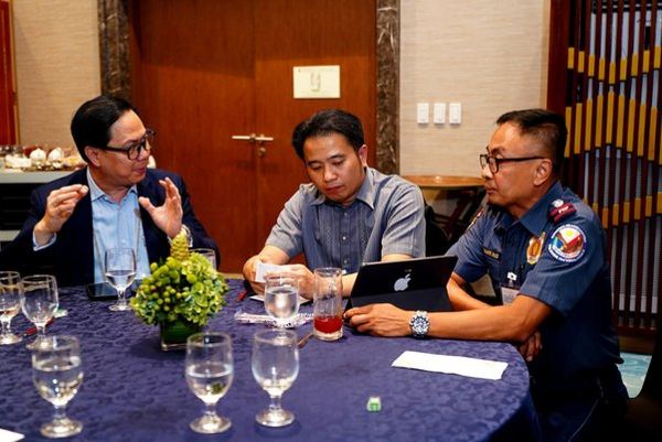 Director Michael Jaey Albaña exchanges ideas with Philippine National Police representatives during the forum, carrying the conversation on police performance beyond the podium and around the table.
