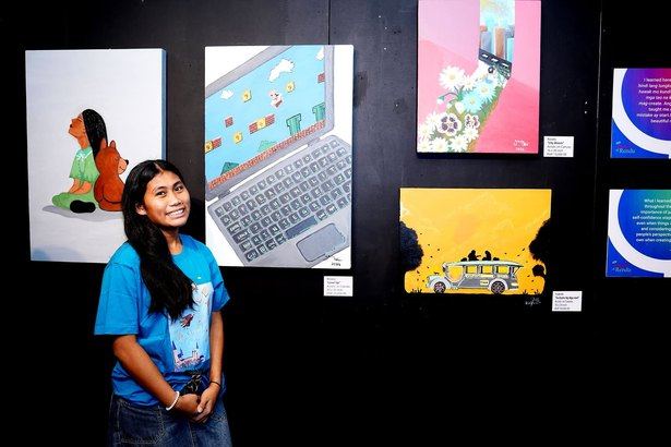 Young artist Rosely proudly stands beside her painting Level Up at Beyond Limits. Her bright smile mirrors the joy of sharing her creativity, a meaningful milestone in her journey with the Angels of Rendu.