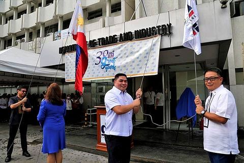 Officials and staff of the Department of Trade and Industry stand alongside Macatoman during a ceremonial flag-raising for the agency’s anniversary celebration honoring decades of service to Philippine trade and industry.